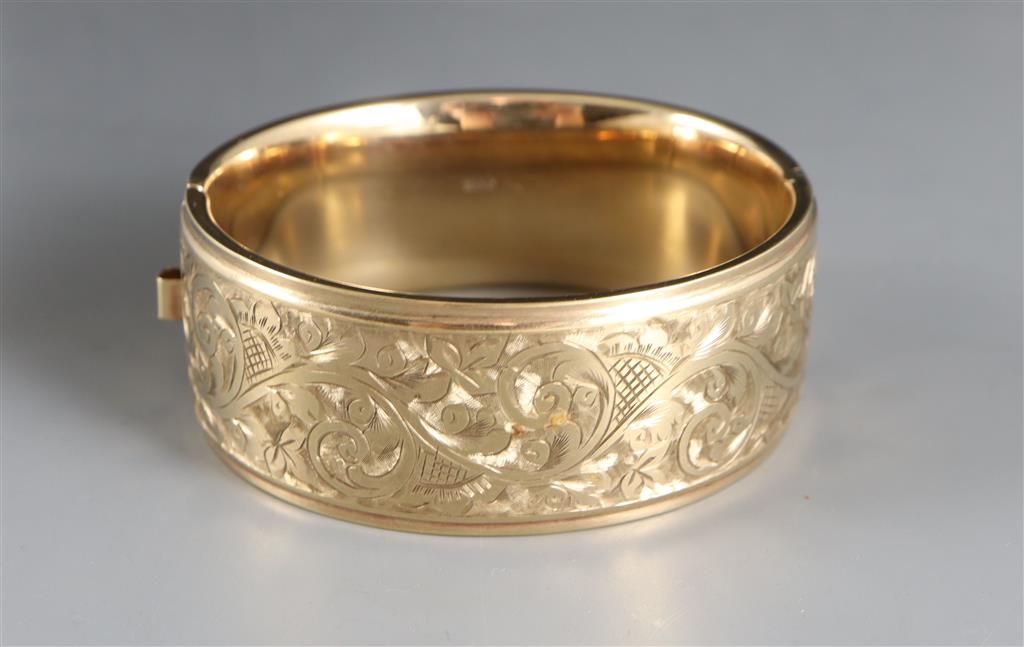 A late 1950s engraved 9ct gold hinged bangle,